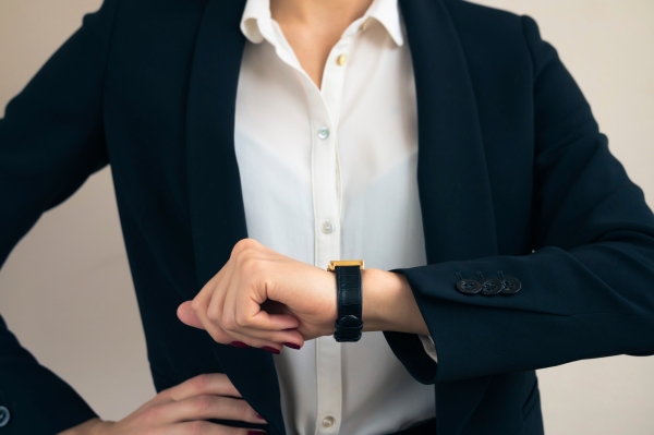 Woman in business suit looks on the hand of the clock close up