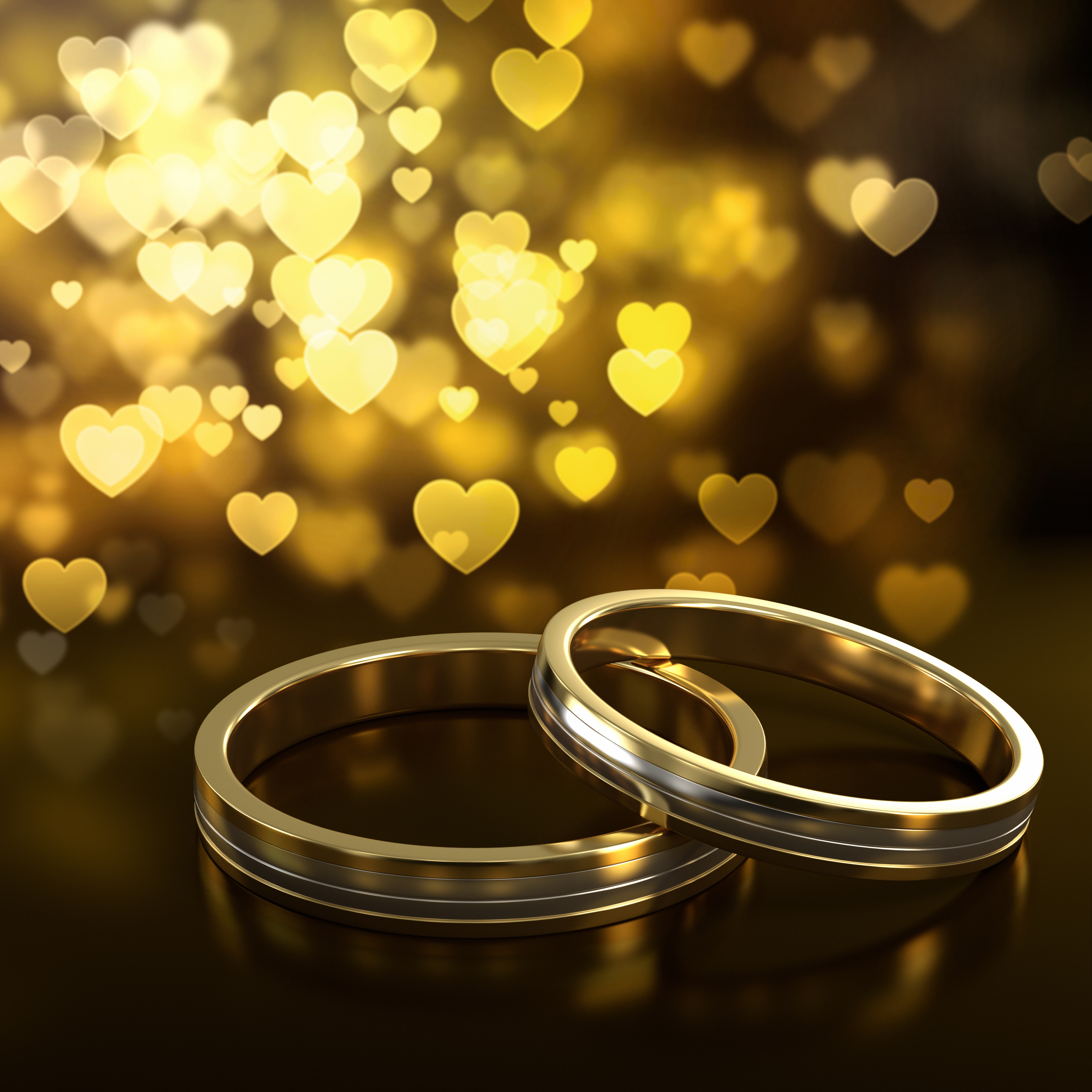 Two golden wedding rings with heart bokeh on background